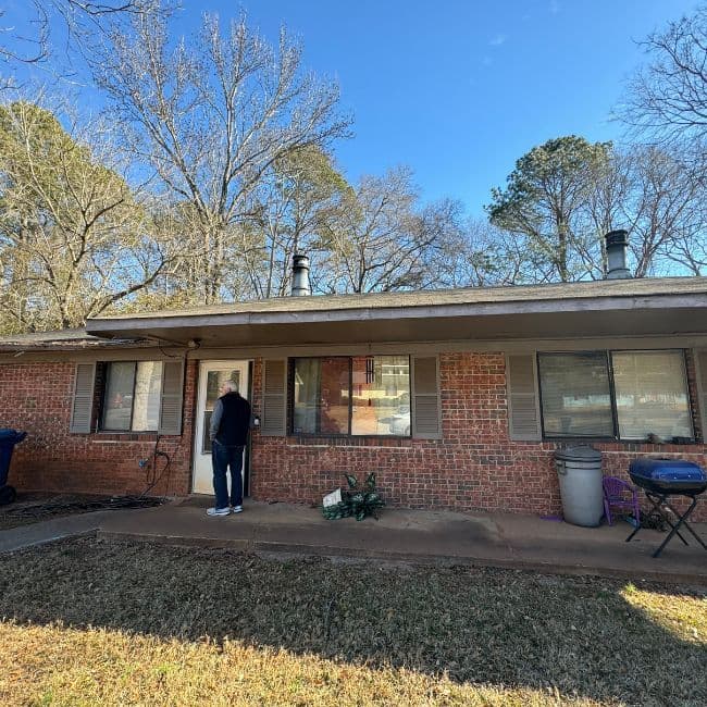 Brick ranch-style home with a person near the front door.